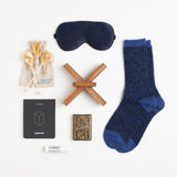 Soft but rugged alpaca socks, a classic deck of cards, moisturizing lip balm and a navy silk eye mask make recuperating as pleasant as possible.