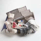 A luxe alpaca blanket, cashmere mix slouch socks, organic lip balm, and a deck of playing cards designed in tribute to Ray and Charles Eames provide a true at-home oasis.