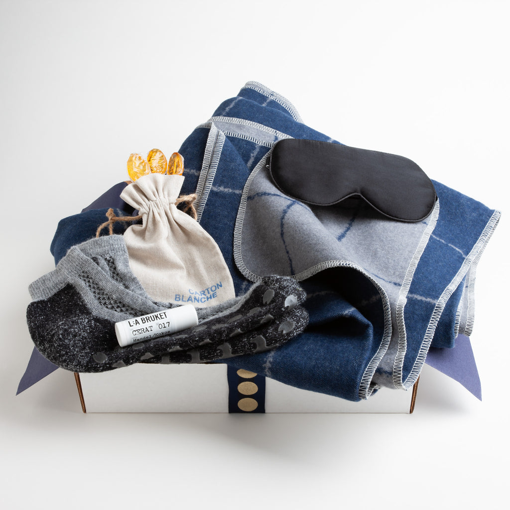 In rich shades of indigo and grey, this reversible blanket from David Fussenegger is destined to be a favorite. Combined with a black silk eye mask, alpaca non-slip socks, soothing lip balm, and clover honey spoons, this wellness gift is sure to make anyone feel more comfortable.