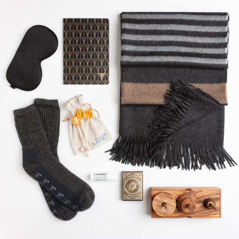 A silk eye mask, cozy non-slip socks, and a soft alpaca blanket provide the basics for a comfortable recuperation, while a classic wooden game and James Bond-themed playing cards provide some needed intrigue.