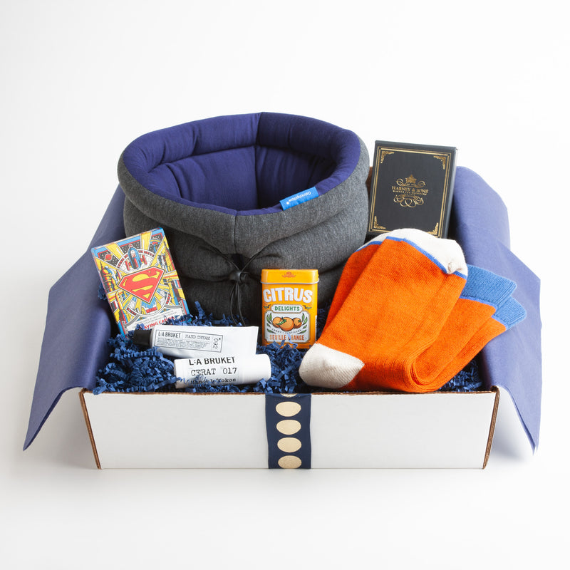 This zesty carton is chock full of items that even a superhero would love. The "versatile" pillow from Ostrich Pillow doubles as an eye mask/pillow and makes any sleeping or sitting position more comfortable. Striking color block socks, a colorful tea assortment, nourishing lip balm, and hand cream by LA Bruket, as well as a vibrant deck of Superman playing cards round out this multifaceted gift.