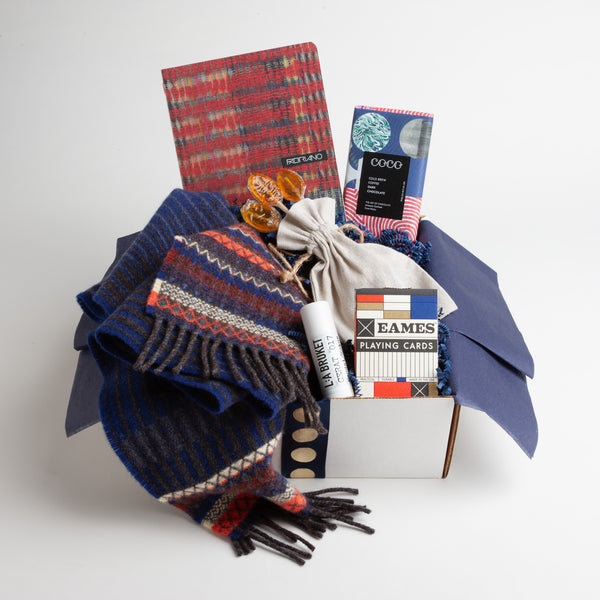 A natty lambswool scarf, combined with a kicky plaid notebook, extra-large lip balm, and a coffee-infused dark chocolate bar make for a stylish way to embrace the winter, even if it's only from the comfort of your couch.