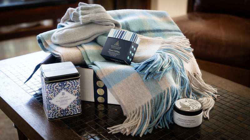 This gift is designed to envelop the receiver in blissful comfort. It includes a lovely lambswool throw, cozy angora socks, a nourishing hand and body cream, and refreshing pomegranate green tea, making it an ideal companion for peaceful moments at home.