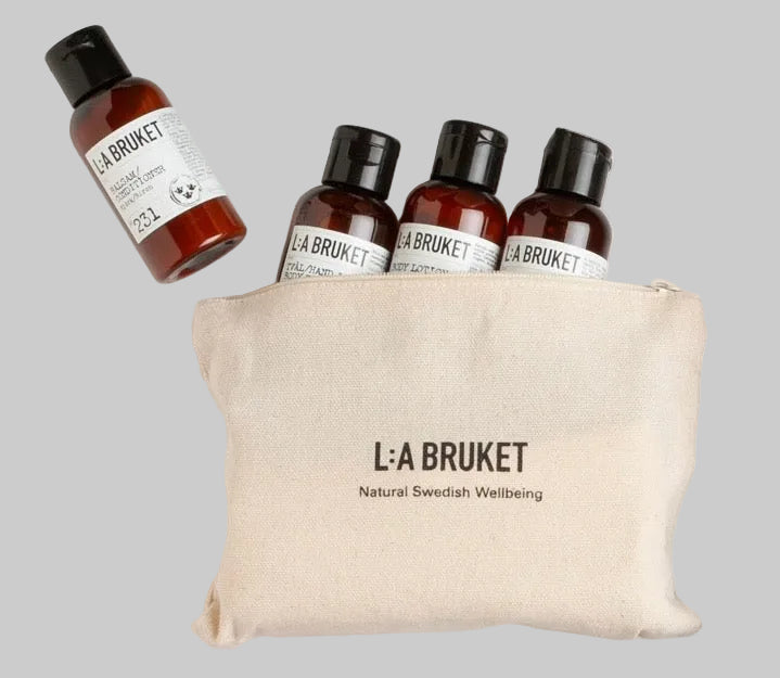 LA Bruket Discovery Kit containing four small amber bottles of body wash, hand wash , shampoo and conditioner in a branded natural linen bag. w