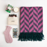 A lively pink and emerald lambswool throw, angora bed socks, a sea salt dark chocolate bar, a floral scented candle, and an LA Bruket organic skincare travel kit.
