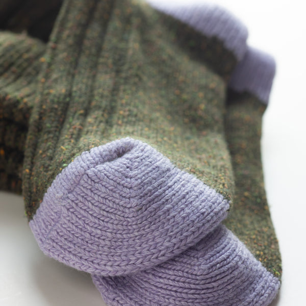 Dark Green Silk Blend Socks by Catherine Tough: These cozy socks have a satisfyingly chunky rib design, but are soft enough to be worn as bed socks. The dark green silk yarn has tweed-like flecks of color throughout, and is accented by lilac heels. Made from virgin silk, lambswool, viscose, and nylon, the socks are a recycled blend of high-quality, Italian spun yarn. Size: 8.5-11.5 US.