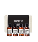 LA Bruket Discovery Kit containing four small amber bottles of body wash and hand wash with black caps, displayed in front of a black and white branded box.