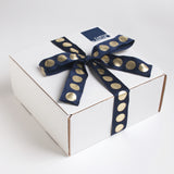 All of our gifts come in our trademark white carton and are tied up with a festive navy and metallic gold dotted ribbon.