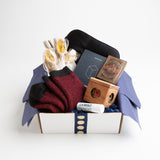 Soft but rugged alpaca socks, a black silk eye mask, moisturizing lip balm, and a regal deck of playing cards are the perfect wellness accessories for lounging around in style.