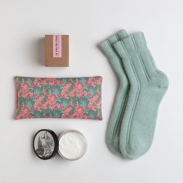 A pair of peppermint angora socks are paired with a floral eye pillow, rich moisturizer in vintage peony and a natural candle infused with tuberose and orange peel.