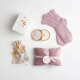 A luxe velvet heat pillow, soft angora bed socks, a botanical travel candle and a colorful tea sampler from TeaLeaves work together to create a sense of peacefulness and calm.
