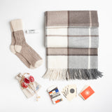 A luxe alpaca blanket, cashmere mix slouch socks, organic lip balm,  and a deck of playing cards designed in tribute to Ray and Charles Eames provide a true at-home oasis.   